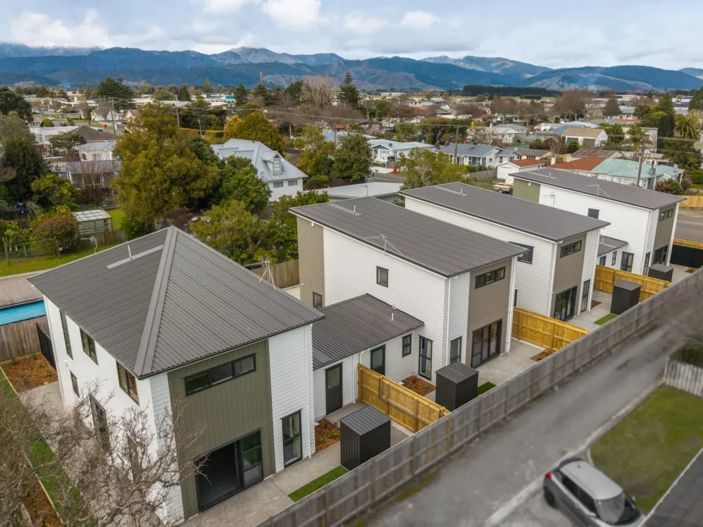 Multi-unit residential development with green-grey cladding and a shared driveway