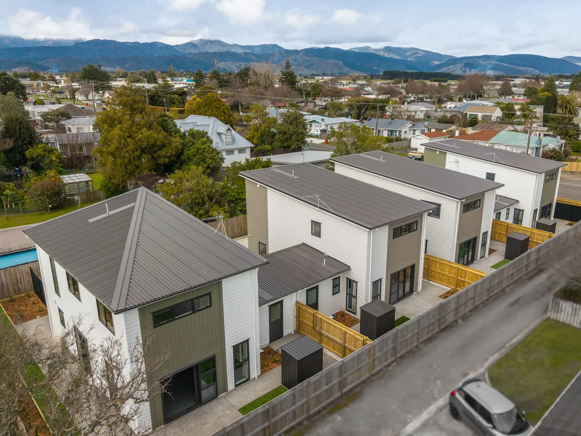 Multi-unit residential development with green-grey cladding and a shared driveway
