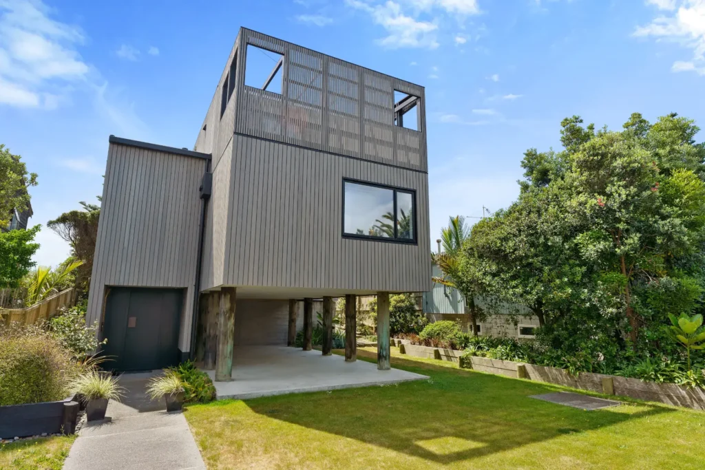 Contemporary cube-form home at 7 Tutere Street, Waikanae Beach, with dark cladding and large glazing