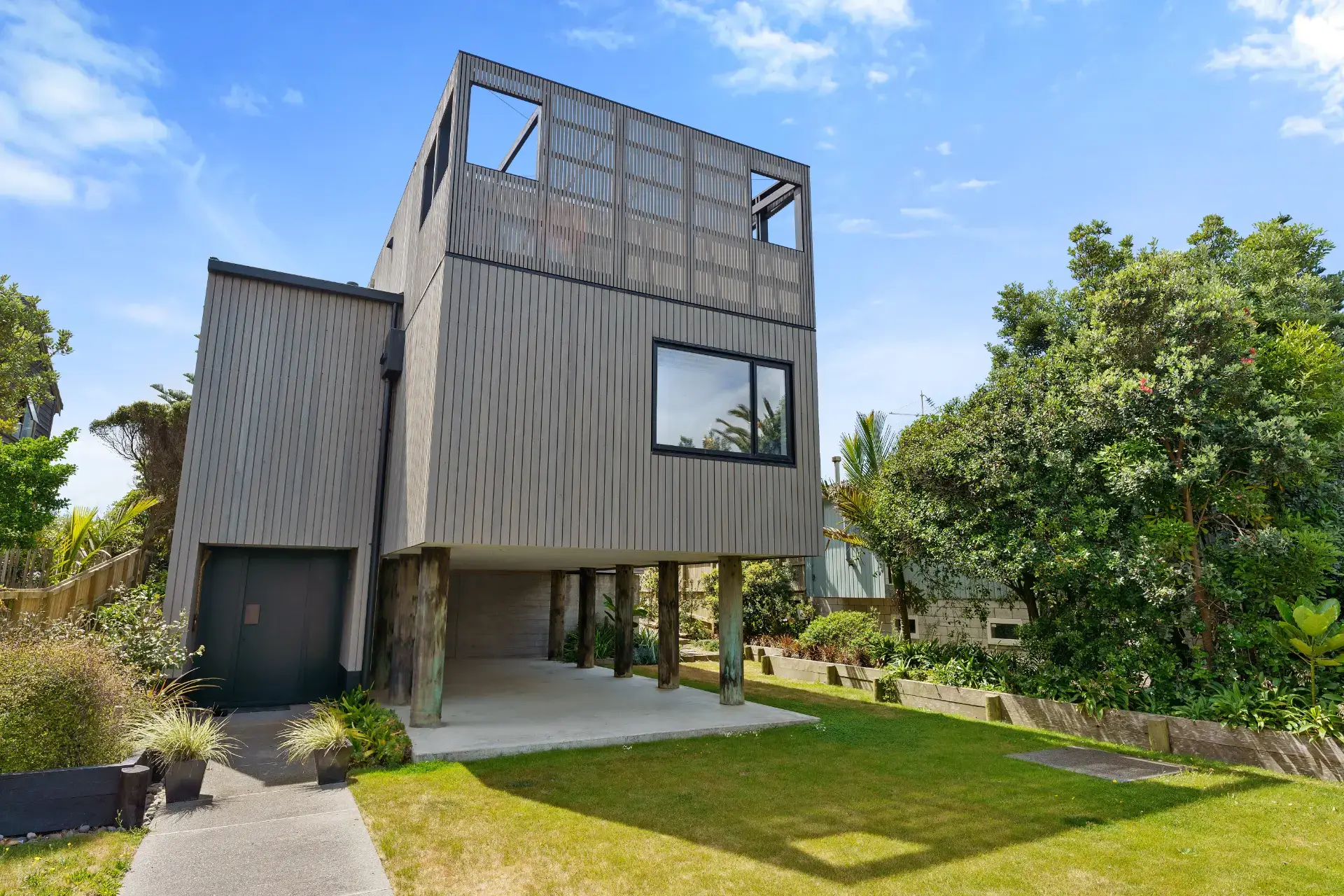 Contemporary cube-form home at 7 Tutere Street, Waikanae Beach, with dark cladding and large glazing