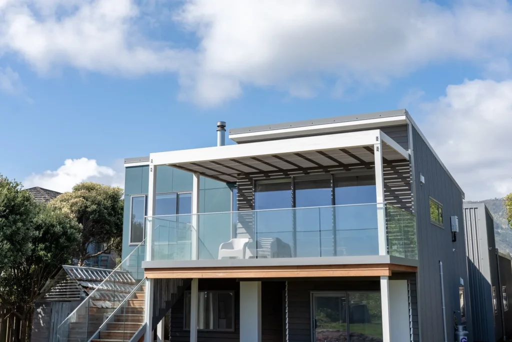 Beachfront Living Elevated - two-storey front elevation with sea-view deck, louvred pergola and floating external stair